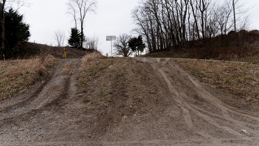 Oh, the road is like 10 feet DOWN behind the sign.  As you can see, people have been missing the turns for a long time.